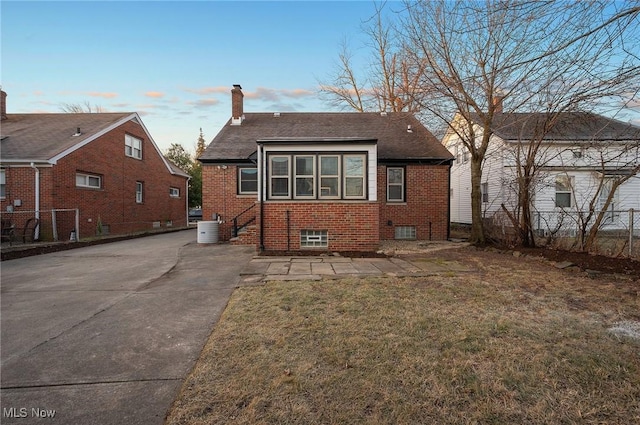 back of house with brick siding, cooling unit, a chimney, and fence