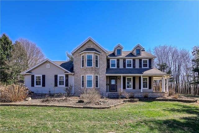 shingle-style home with a front lawn and stone siding