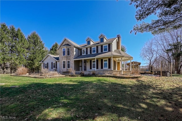 view of front of house featuring a front lawn, covered porch, stone siding, and a chimney