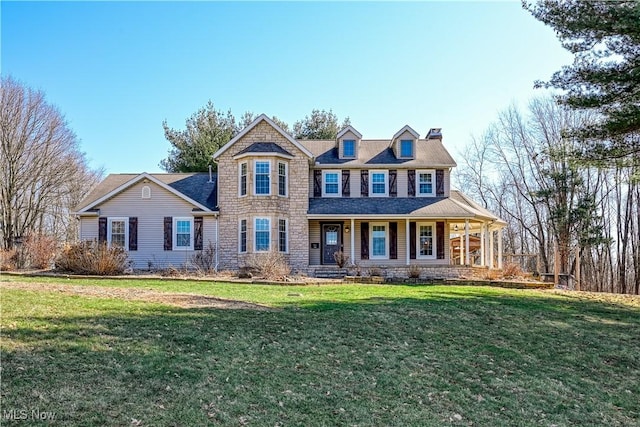 view of front of home featuring stone siding, a porch, a chimney, and a front yard