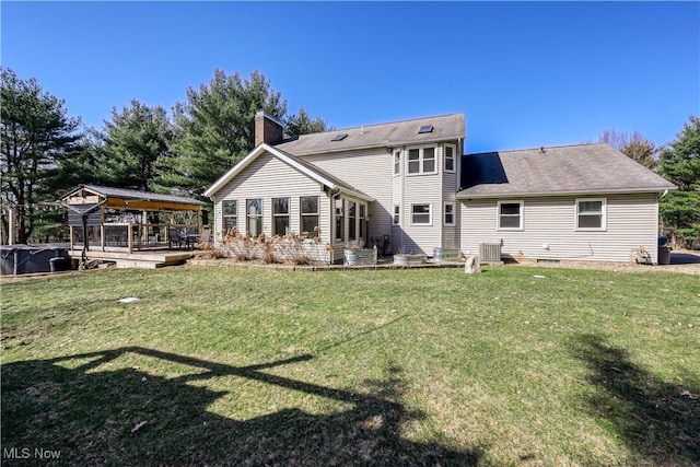 back of property with central air condition unit, a yard, roof with shingles, and a chimney