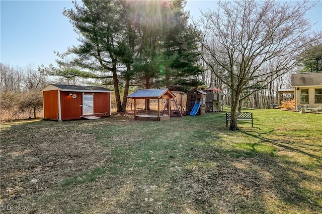 view of yard with an outdoor structure, a playground, and a shed