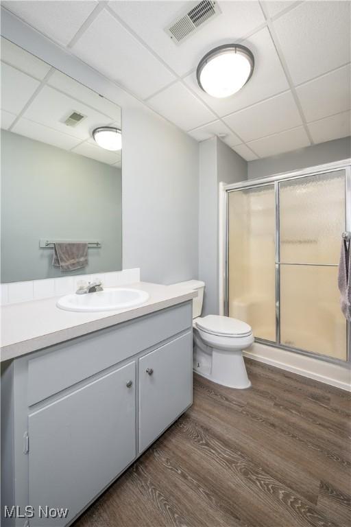 bathroom with visible vents, toilet, a stall shower, wood finished floors, and vanity