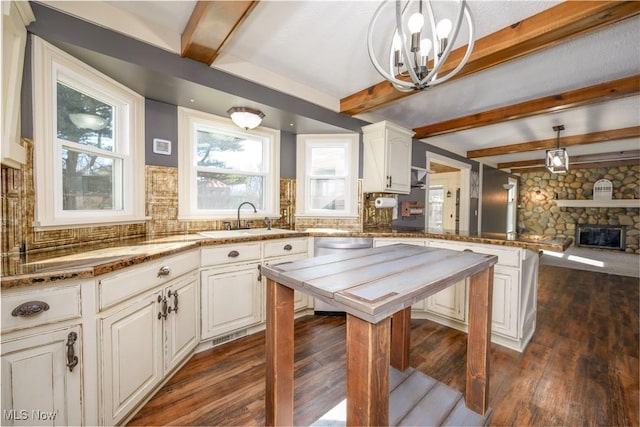 kitchen with a notable chandelier, a sink, backsplash, dark wood-style floors, and a peninsula