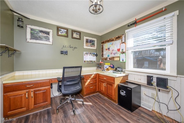 office area with dark wood finished floors, a textured ceiling, a wainscoted wall, and built in study area