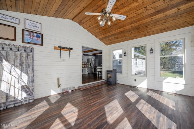 unfurnished sunroom with lofted ceiling, a wood stove, wood ceiling, and ceiling fan