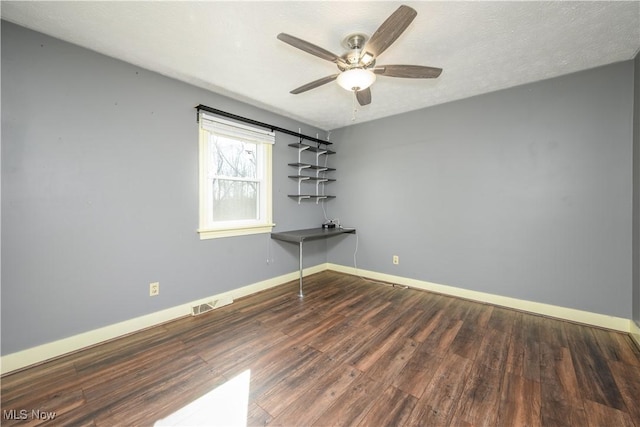 unfurnished room with a ceiling fan, wood finished floors, visible vents, and baseboards