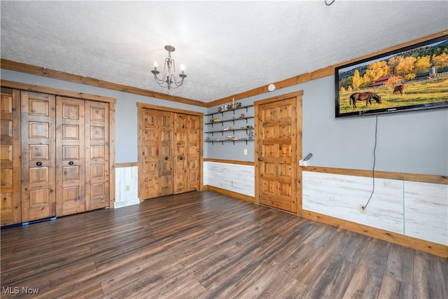 unfurnished bedroom featuring a textured ceiling, an inviting chandelier, and wood finished floors