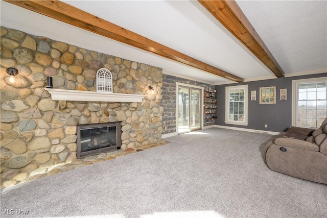 unfurnished living room with a stone fireplace, beamed ceiling, baseboards, and carpet floors