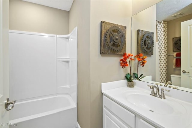 bathroom with vanity,  shower combination, toilet, and visible vents