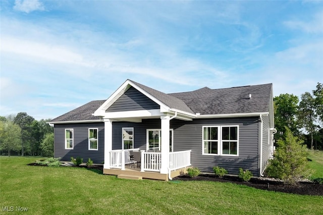 rear view of house with a deck, a shingled roof, and a yard