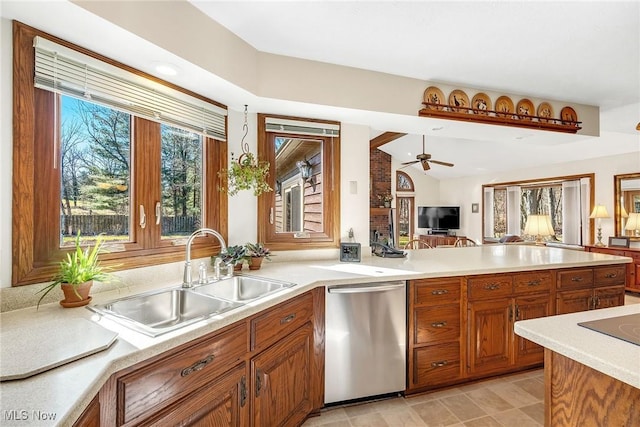 kitchen featuring brown cabinetry, ceiling fan, a sink, light countertops, and stainless steel dishwasher