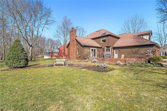 rear view of house featuring brick siding, a lawn, and a chimney