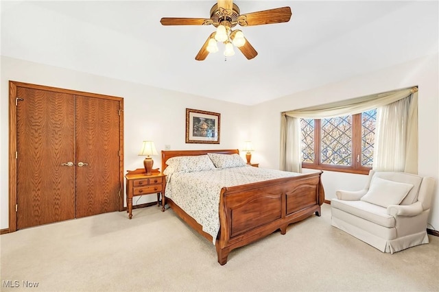 bedroom featuring light colored carpet, baseboards, and a ceiling fan