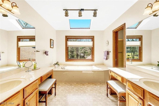 full bathroom with a skylight, two vanities, a garden tub, and a sink