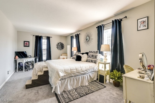 carpeted bedroom featuring baseboards and multiple windows