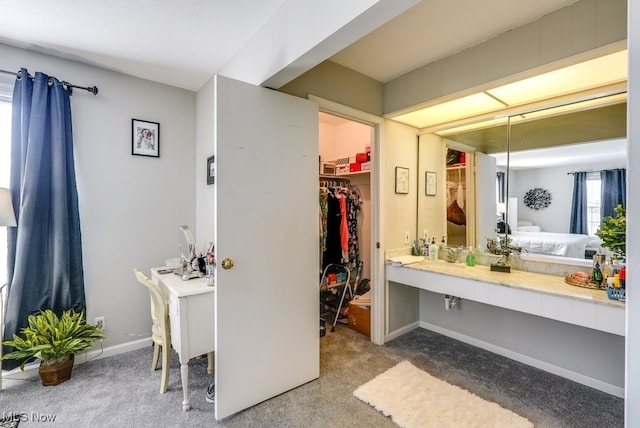 bathroom with a walk in closet, baseboards, and connected bathroom