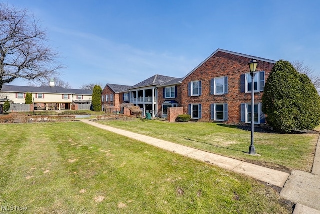 view of front of property featuring a residential view, brick siding, and a front yard