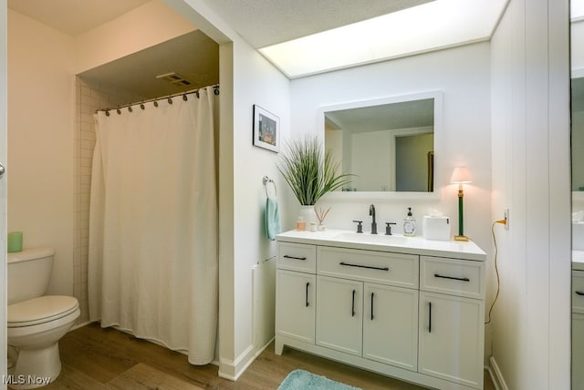 bathroom with vanity, toilet, wood finished floors, and visible vents