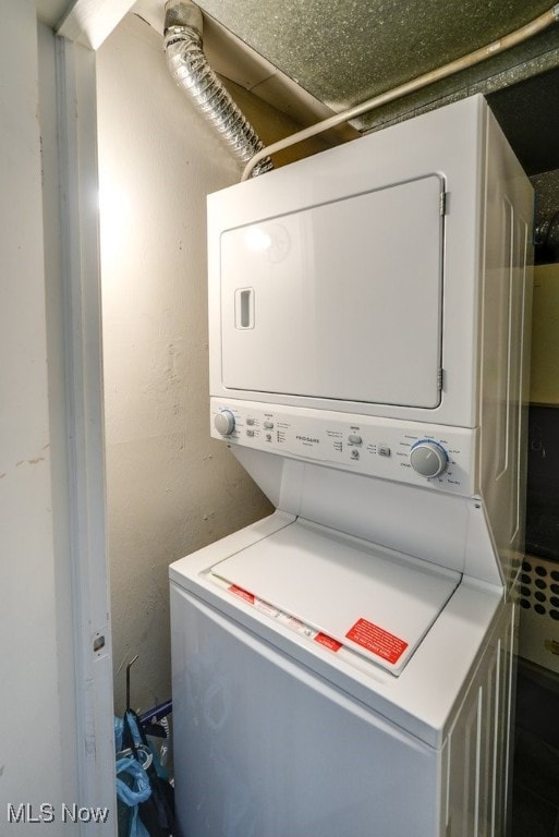 washroom with laundry area, stacked washing maching and dryer, and a textured wall