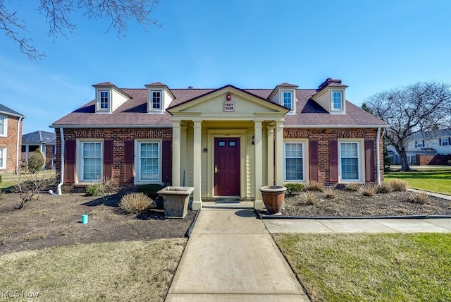 greek revival house featuring brick siding and roof with shingles