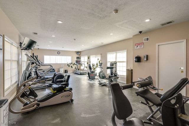 workout area featuring visible vents, plenty of natural light, and a textured ceiling