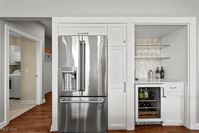 kitchen featuring wine cooler, washer / dryer, high quality fridge, dark wood-style floors, and white cabinets