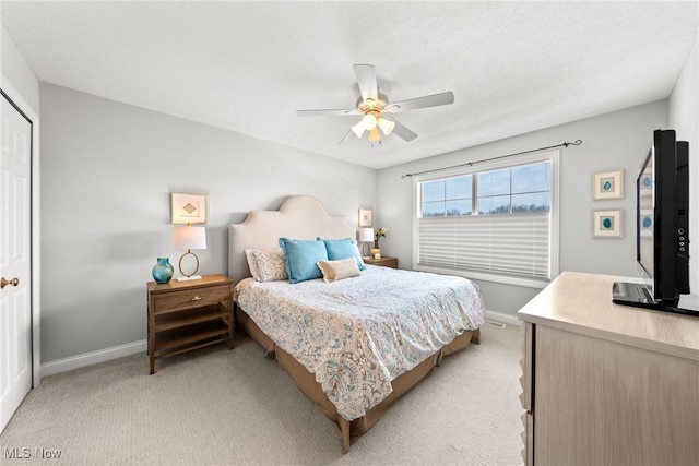 bedroom featuring light carpet, ceiling fan, and baseboards