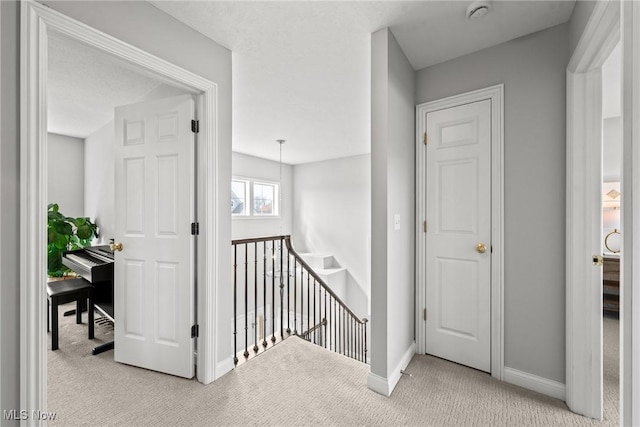 hall with carpet, an upstairs landing, and baseboards