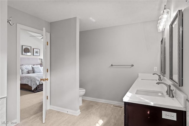 ensuite bathroom with toilet, baseboards, ensuite bathroom, and a sink