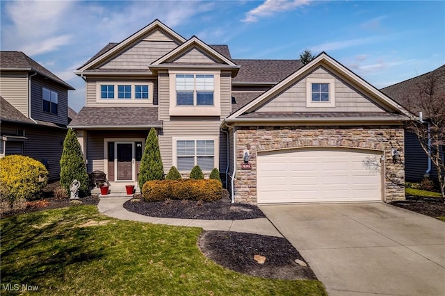 craftsman-style home featuring a front yard, stone siding, driveway, and roof with shingles