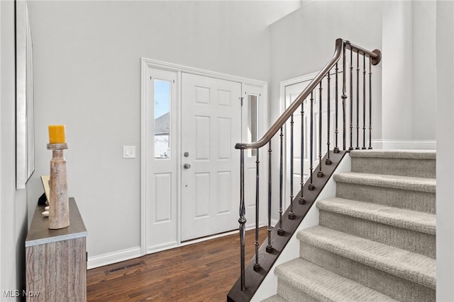 foyer with dark wood finished floors, stairway, baseboards, and visible vents