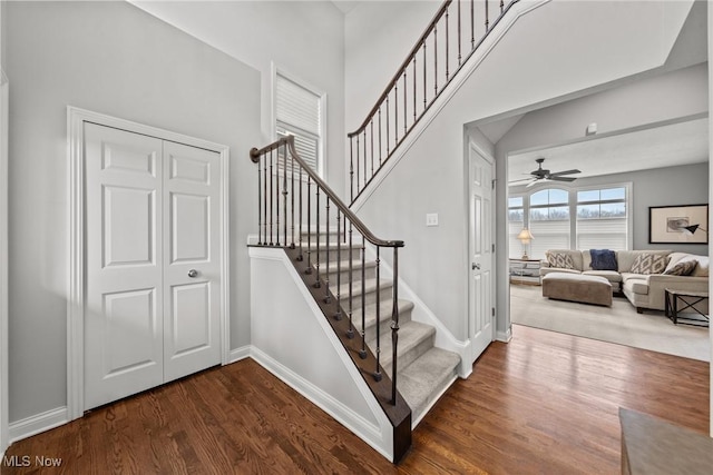 staircase with ceiling fan, baseboards, and wood finished floors