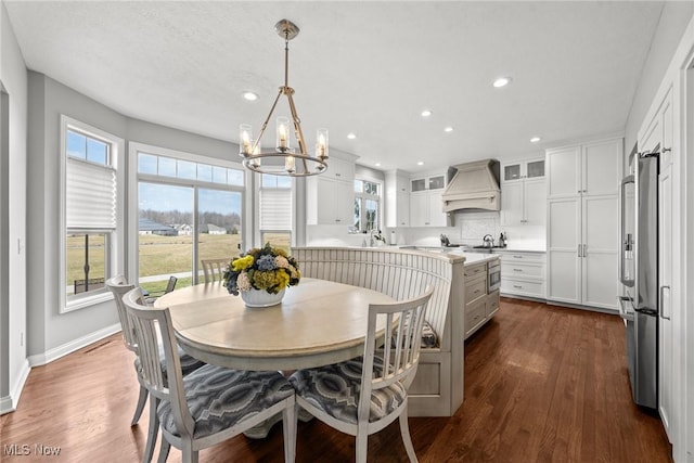 dining area with a wealth of natural light, baseboards, dark wood-type flooring, and an inviting chandelier