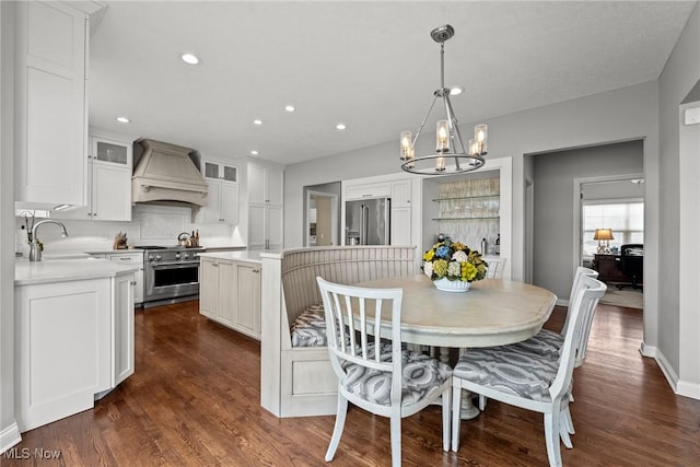 dining area with recessed lighting, baseboards, an inviting chandelier, and dark wood-style flooring