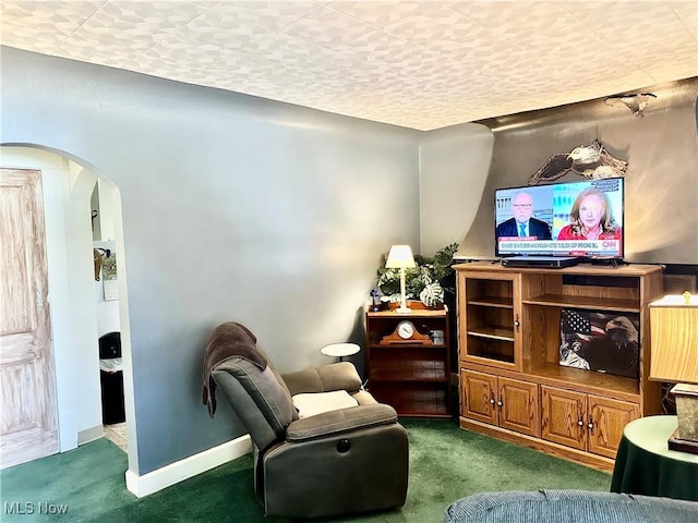 living area with carpet flooring, baseboards, and arched walkways