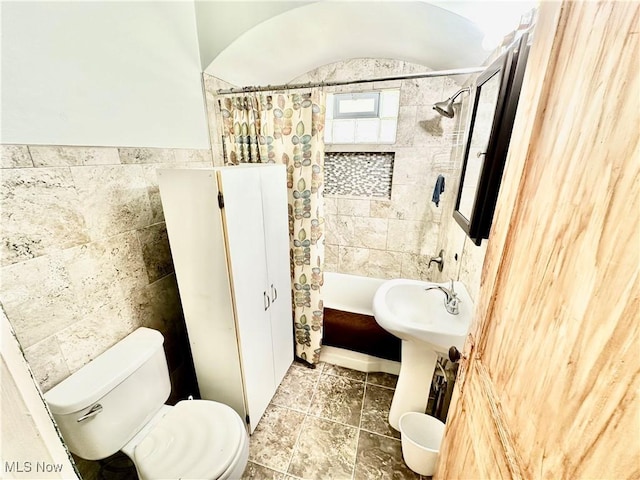 full bathroom featuring toilet and tile walls