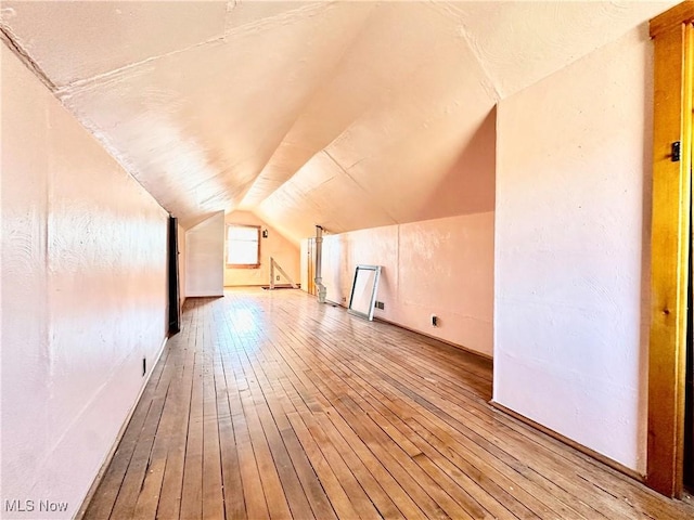 bonus room with wood-type flooring and vaulted ceiling