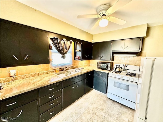 kitchen featuring a ceiling fan, a sink, under cabinet range hood, white appliances, and decorative backsplash