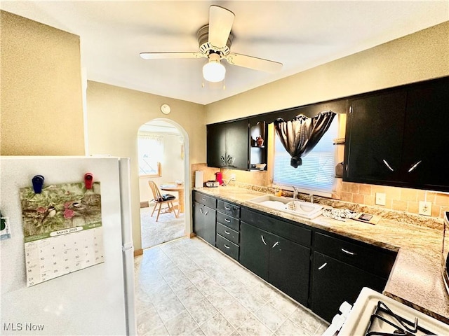 kitchen with a sink, arched walkways, and dark cabinets