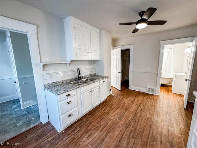 kitchen featuring dark wood finished floors, decorative backsplash, white cabinets, and a sink