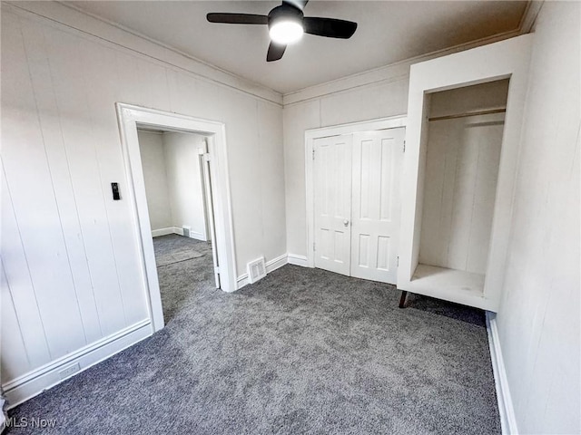 unfurnished bedroom featuring crown molding, visible vents, dark carpet, and ceiling fan