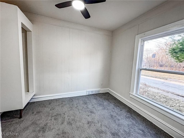 unfurnished room featuring visible vents, a ceiling fan, a healthy amount of sunlight, and dark carpet