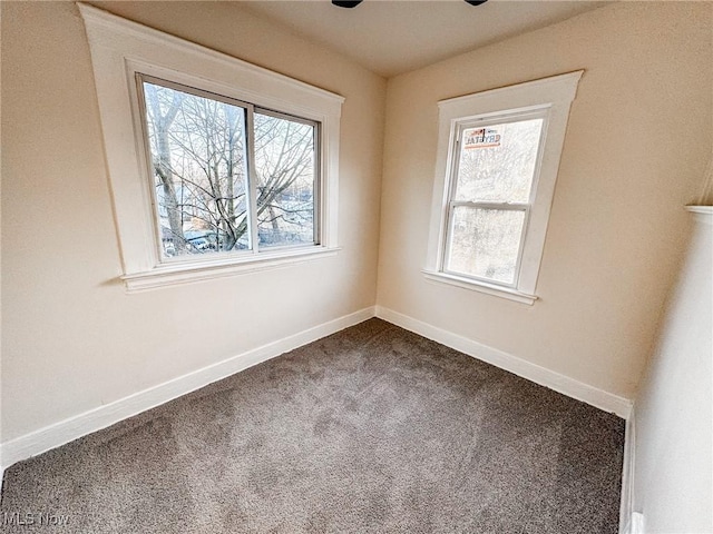 spare room with baseboards and dark carpet