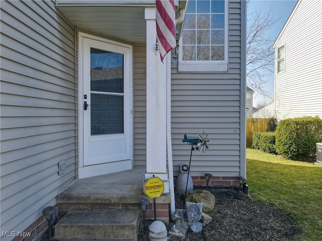 property entrance featuring a lawn and fence