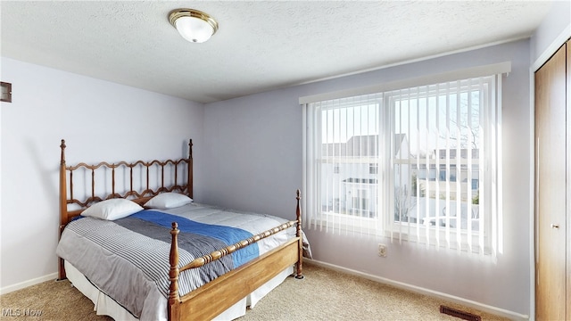 carpeted bedroom featuring visible vents, a textured ceiling, and baseboards