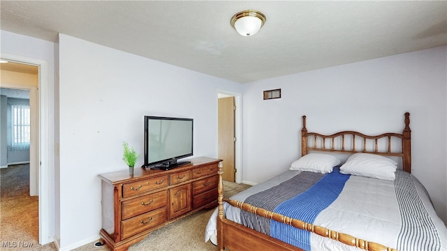 bedroom with light colored carpet and baseboards