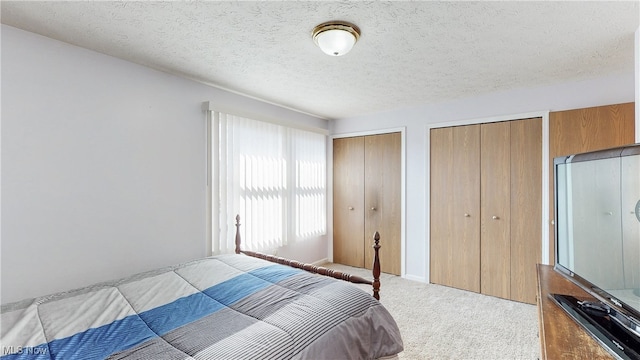 carpeted bedroom featuring a textured ceiling and multiple closets