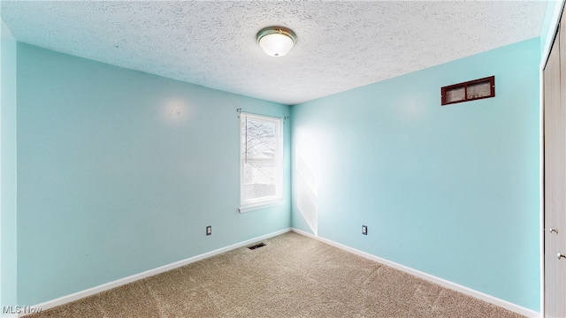 spare room featuring visible vents, a textured ceiling, baseboards, and carpet