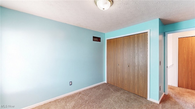 unfurnished bedroom featuring a closet, baseboards, carpet, and a textured ceiling